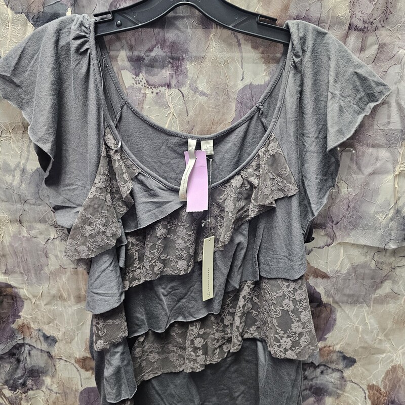 Brand new with tags and retails for $36. This blouse is done in a grey knit with all the ruffles and lace.