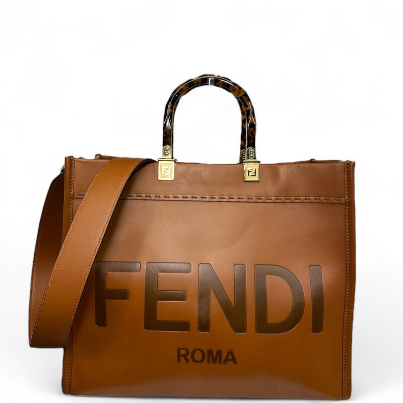 Fendi Sunshine Tote, Brown, Size: Medium

Dimensions:
Height : 31 cm
Depth : 17 cm
Width : 35 cm
Weight : 1.2 kg
Strap length (min) : 90 cm
Strap length (max) : 90 cm
Shoulder strap drop : 40 cm

Note: Srtach on front, mark from handles, and light sratches on back.

Medium Fendi Sunshine bag, a roomy, versatile city shopper distinguished by its linear design and sophisticated details.
Made from brown calfskin with hot-stamped Fendi Roma and stiff plexiglass handles with a tortoiseshell effect.
Features a spacious lined internal compartment, edges in tone-on-tone leather, and gold-finish metalware.
Can be carried by hand or worn on the shoulder thanks to the two handles and detachable shoulder strap.