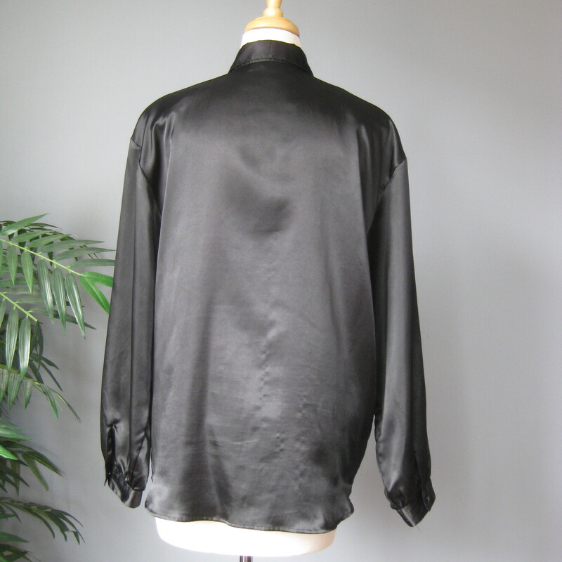 This long sleeved black satin blouse sports large metal set plastic jewels.<br />
It's such an 80s iconic piece!<br />
by Laura & Jayne Collection.  Buttons up the front in a hidden button placket<br />
BIG shoulder pads<br />
Curved hem<br />
button cuffs<br />
This would fit  a modern medium generously, or a large<br />
Here are the flat measurements, please double where appropriate:<br />
Shoulder to shoulder: 20<br />
Armpit to Armpit: 22.5<br />
Width at hem: 23<br />
Underarm sleeve seam: 17.5<br />
Length: 29.5<br />
<br />
Excellent vintage condition<br />
Thank you for looking.<br />
#67875