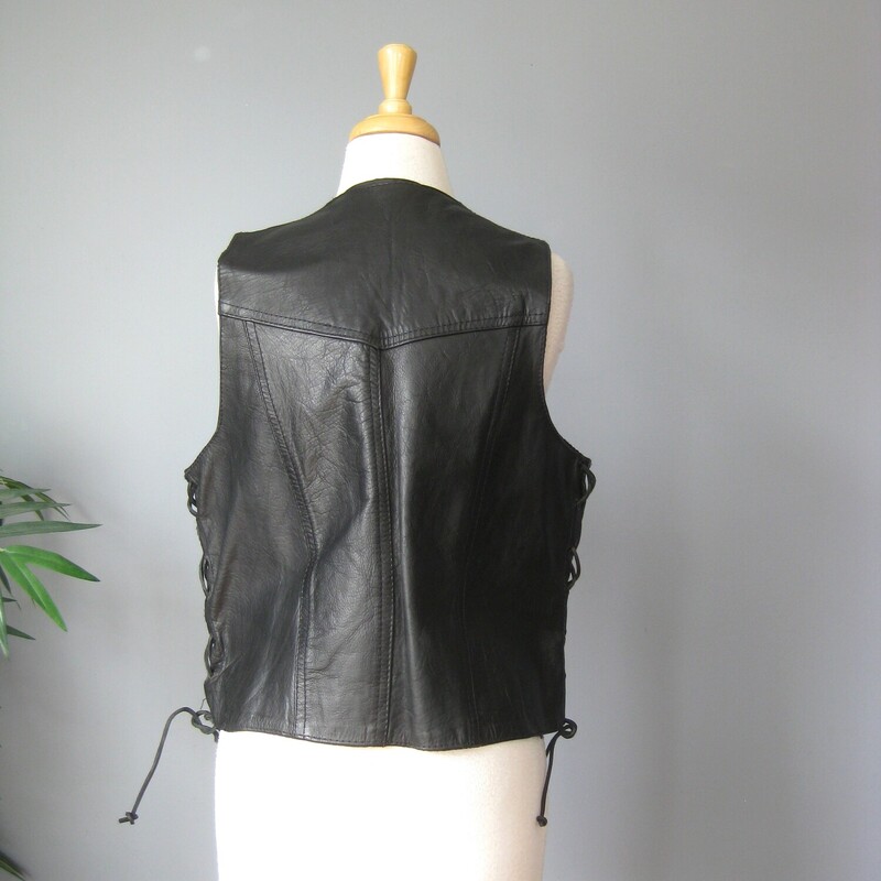 Here's a simple motorcycle vest in black leather. Labeled size medium. The front closes with snaps and the sides are connected with corset lacings so you can adjust the fit to be perfect for you.

The vest is in great condition, the leather supple and smooth.
Fully lined with two pockets on the front.
For me it was a little oversized even at the minimum adjustments, totally wearable. I am am about 38 B with my bra and a shirt on.

Here are the flat measurements, please double where appropriate.
Armpit to Armpit: 20 minimum, can be adjusted a few inches larger with the leather thongs at each side.
Length: aprox 23

thanks for looking!

#68117