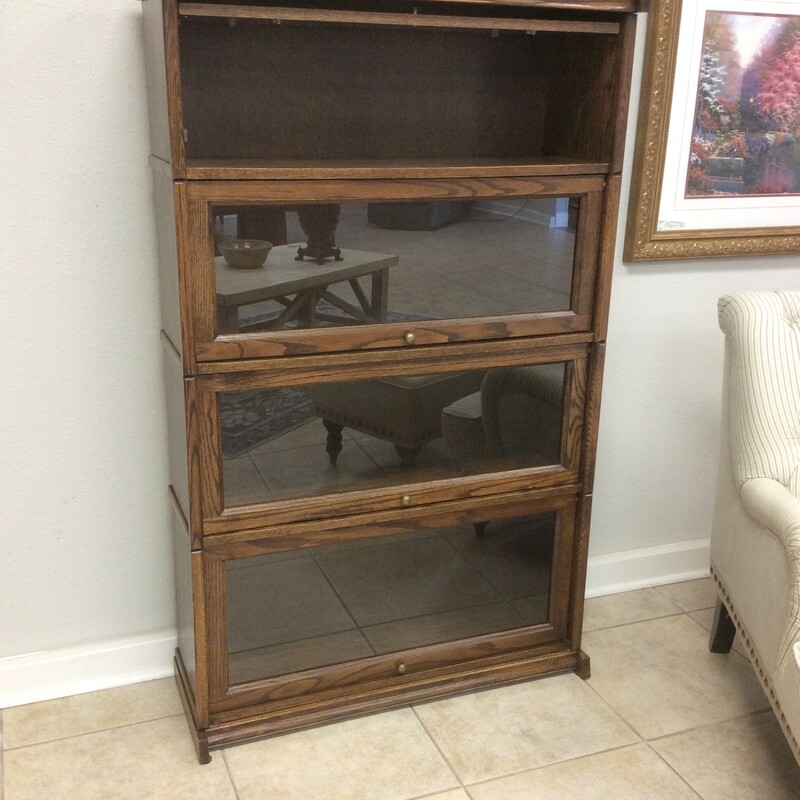 This barrister's bookcase is in very good condition. It features a dark wood finish and has 4 glass-paned shelves.