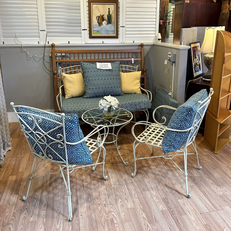 4 Pc. Wrought Iron Patio Set
Love Seat -4 feet long x 2 feet wide x 38 in. tall.
Two chairs - 25 in. from arm to arm x 37 in. tall in back
Seat measures 20 in. long x 19 in. wide.
Glass top table measures 23 in. round x 22 in. tall

Gorgeous, heavy  wrought iron patio set is solid! This has some wear but it has not changed the quality of this set. It can easily be spray painted any color that you wish.
The glass on round table is thick and is not attached.