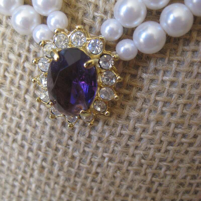Avon Faux Pearl Set, Purple, Size: None<br />
Vintage Avon Jewelry Set<br />
a double strand of faux pearls with a central amethyst colored stone surrounded by rhinestones set in gold tone metal.<br />
the set comes with a pair of stud earrings consisting of a garnet colored stone surmounted by a round rhinestone.<br />
<br />
the necklace has a hook clasp and measures 23 in total length<br />
the earrings are about 1/2 long<br />
<br />
box is original but a little beat up as shown.<br />
<br />
thanks for looking!<br />
#72699