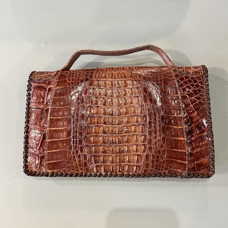 Vtg Alligator Purse,
Size: 9x6
Vintage alligator clutch with a handle on top  It is in very good condition with no rips, tears or stains.  The edges are laced and the clutch snap is intact and works.  There are two sectons in side and a zippered compartment.