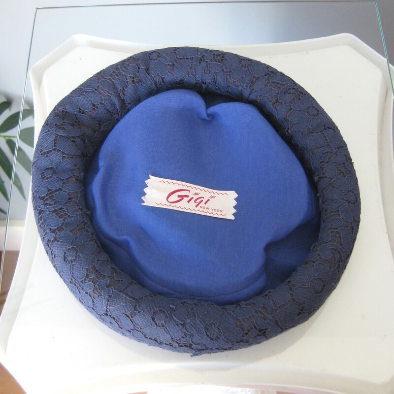 This is a flat round hat made from a stiff body and a blue lace covering.<br />
It's by Gigi.<br />
You'll need a pin or two to secure it into your hair and you can wear it tilted, towards the front or the back.<br />
It's medium navy blue<br />
Excellent condition, no flaws<br />
<br />
The hat measures 20.5 around the inner hat band.<br />
thanks for looking!<br />
#65544