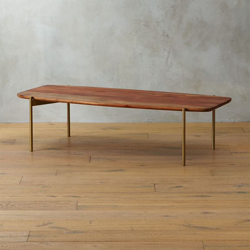 CB2 Adam Coffee Table - Acacia Wood and Brass

 Size: 55Lx39Wx29T

Sleek span of solid sustainable acacia wood rounds the corner with refined proportions and a beam of gleam. Handcrafted with smooth contours, top reveals natural beauty of the wood, stained light brown to highlight varying tones, active grain and natural markings that make each unique. Elevates the room in slick contrast on brass stiletto legs that align precisely with table's edge. adam coffee table is a CB2 exclusive.  -Handcrafted -Solid sustainable acacia wood; unique grain and markings make each unique -Water-based lacquer top-coat -Brass powdercoated stainless steel legs -Wipe with soft, dry cloth -Made in India