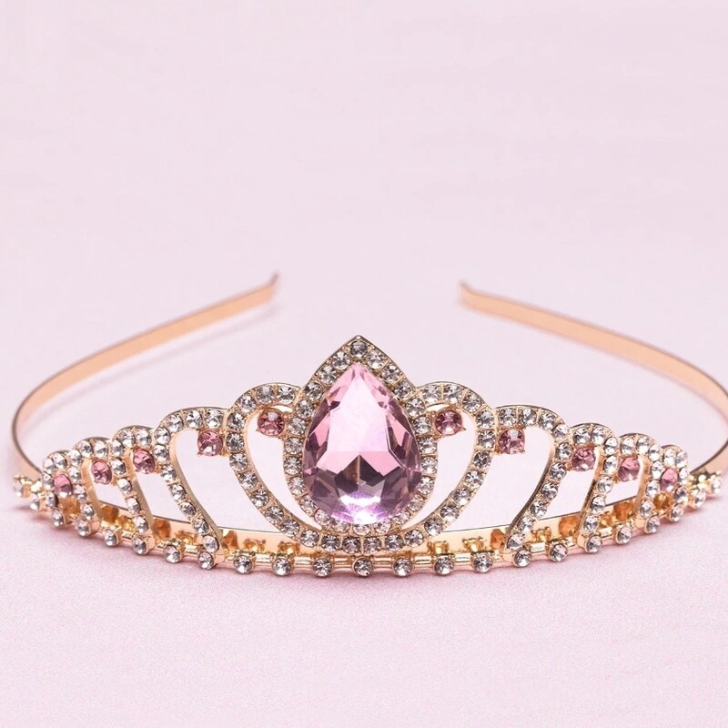 Introducing our exquisite Regal Pink Tiara, a stunning accessory fit for royalty. Crafted with precision and adorned with captivating details, this tiara embodies elegance, grace, and sophistication. It is the perfect crowning jewel for those seeking a touch of regal charm.

The Boutique Regal Tiara boasts a mesmerizing design that effortlessly captures attention. The delicately crafted rose gold base provides a solid foundation, ensuring durability and a comfortable fit. Encrusted with shimmering rhinestones & a large teardrop gemstone, this tiara exudes a radiant sparkle that illuminates any occasion.