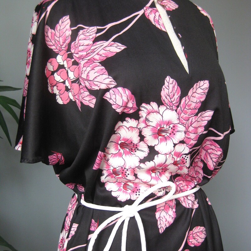 Pretty floral top with a black background and large pink flowers
no tags or labels but it is made with nylon knit, with some stretch.
It has a slit at the neckline with a single button
It has wide cut on sleeves, slits at the end of the side seams, and a pocket on one side.
Comes with a matching cord belt in white
pulls on over the head.
it will serve as a cute top, a VERY short dress or beach coverup or a short robe.


Here are the flat measurements, please double where appropriate:

Armpit to armpit: 21.5
waist area: 20
hip area: 21
Length: 34
slits: 4.5

Excellent vintage condition.

Thanks for looking!
#71620