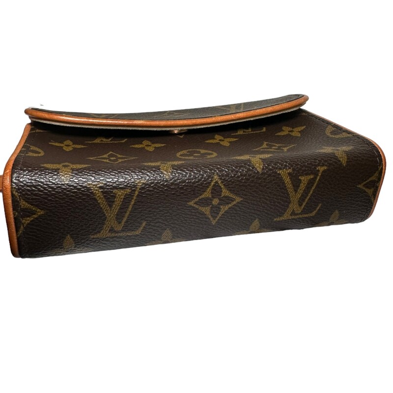 LOUIS VUITTON Monogram Pochette Florentine size M. The stylish bag is a simple small flap style pouch that is crafted of classic Louis Vuitton monogram on coated canvas with signature vachetta natural cowhide. This bag features an optional strap for around the waist and polished gold hardware. The interior is a beige microfiber.<br />
Code: FL0073<br />
Dimensions:<br />
Base length: 6.5 in<br />
Height: 4.25 in<br />
Width: 1.75 in<br />
Drop: 20 in