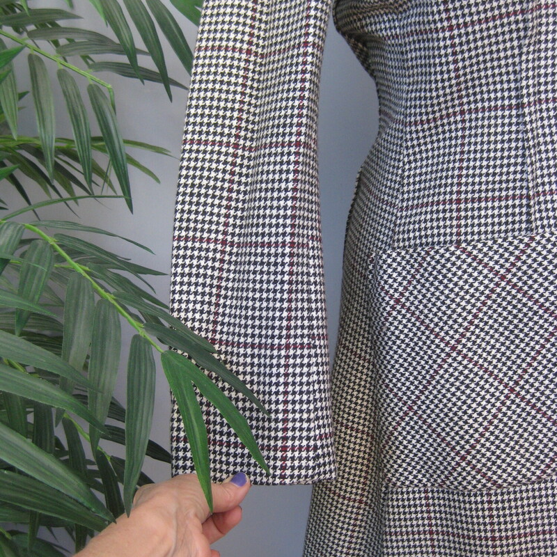 Unique wool coat in a black and white houndstooth check with a red stripe.<br />
The coat has a fit and flare silhouette, close at the top and a full skirt.<br />
It also has a dramatic collar and closure arrangment.<br />
big patch pockets, useful and stylish.<br />
It closes with black plastic buttons<br />
fully lined<br />
union label<br />
<br />
Excellent condition, old but no flaws.<br />
Here are the flat measurements, please double where appropriate:<br />
Shoulder to shoulder: 17<br />
armpit to armpit: 19.5 (measured on the inside of the coat)<br />
waist: 17 (also measured on the inside)<br />
hips: 21.5<br />
underarm sleeve seam length: 17.25<br />
overall length: 39<br />
<br />
thanks for looking!<br />
#70406