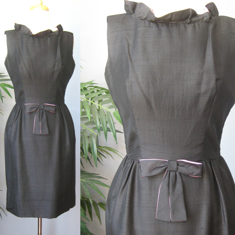 Simple black silk sheath dress from the 1950s with a VERY cute twist and a Jackie Kennedy vibe.
Fitted at the waist with a darling bow and a relaxed ruffled high neck. The bow and the neckline are lined with baby pink.

No fabric or band id tags. But almost certainly silk shantung.
unlined
Center back metal zipper

marked size 11, but disregard that number! vintage sizes have nothing to do with modern sizes.
This dress fits my size 4 mannequin well.
Pls use flat measurements below:
Armpit to Armpit: 19.5
Waist: 13.25
Hips: 19.5
Overall Length: 37 - it is unlined and the hem is deep. You can easily change the hem to make it shorter BUT!! the fabric turned under for the current hem has some significant discoloration due to being stored on a hanger and inside out for many years before I bought it. So you can make it shorter if you like but probably not longer.

Thank you for looking
#70443