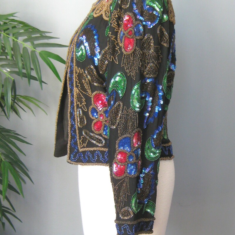 This is a very cool sequined jacket from the 1990s by
Lisiano
it's a little boxy and cropped
substantial
The beaded shell is silk and the lining is rayon
fully lined with shoulder pads.
single hook and eye closure at the neck
gorgeous green red and blue florals with gold accent beading
This jacket is unusded and comes with a small bag of extra beads and sequins
Design covers front and back and sleeves
Made in India
Marked size 10, should fit a modern size small or smaller medium size gal.  I think best for a petite as the length of the jacket and the sleeves is a little smaller than average

interior flat measurements:
shoulder to shoulder: 16
armpit to armpit: 19
length: 19.25
width at hem: 16
underarm sleeve seam length: 15.5
Excellent condition, no flaws
thanks for looking!
#71712