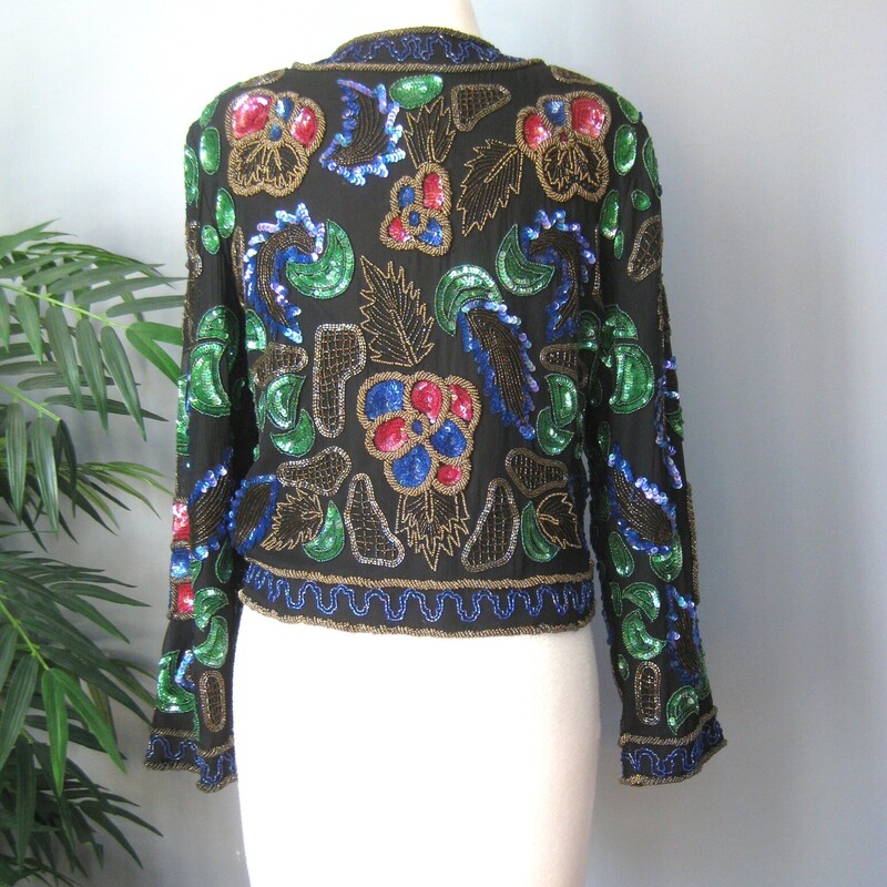 This is a very cool sequined jacket from the 1990s by<br />
Lisiano<br />
it's a little boxy and cropped<br />
substantial<br />
The beaded shell is silk and the lining is rayon<br />
fully lined with shoulder pads.<br />
single hook and eye closure at the neck<br />
gorgeous green red and blue florals with gold accent beading<br />
This jacket is unusded and comes with a small bag of extra beads and sequins<br />
Design covers front and back and sleeves<br />
Made in India<br />
Marked size 10, should fit a modern size small or smaller medium size gal.  I think best for a petite as the length of the jacket and the sleeves is a little smaller than average<br />
<br />
interior flat measurements:<br />
shoulder to shoulder: 16<br />
armpit to armpit: 19<br />
length: 19.25<br />
width at hem: 16<br />
underarm sleeve seam length: 15.5<br />
Excellent condition, no flaws<br />
thanks for looking!<br />
#71712