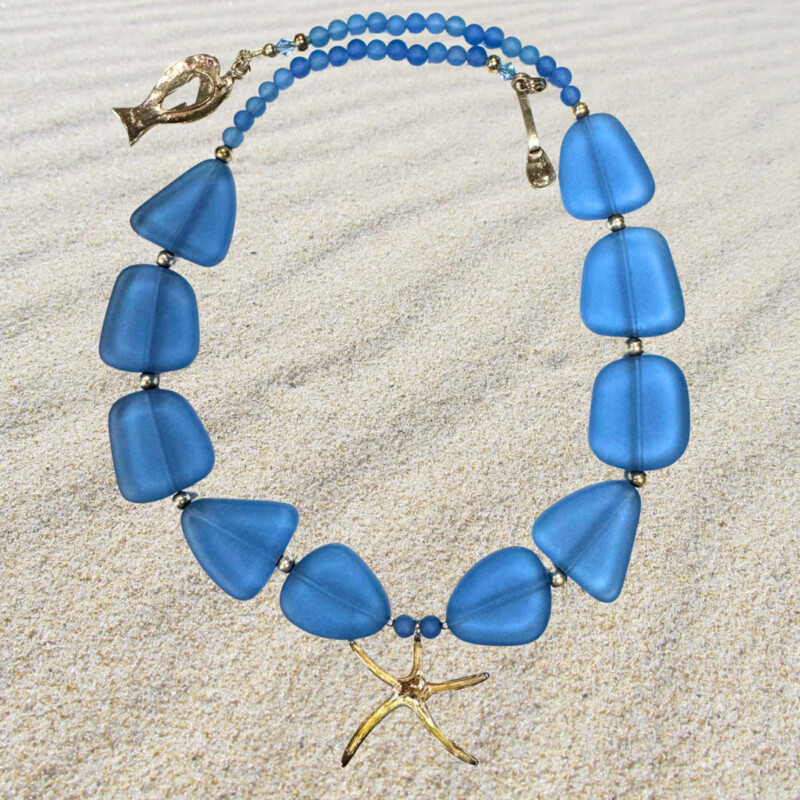 Red Sand Jewelry by Barbara Nymark<br />
Beautiful hand crafted in Victoria-By-The-Sea, PEI, Canada .925 Star Fish and Fishy<br />
Blue SeaGlass Necklace with Swarovski crystals and sterling silver.<br />
<br />
Size: 20 Inches