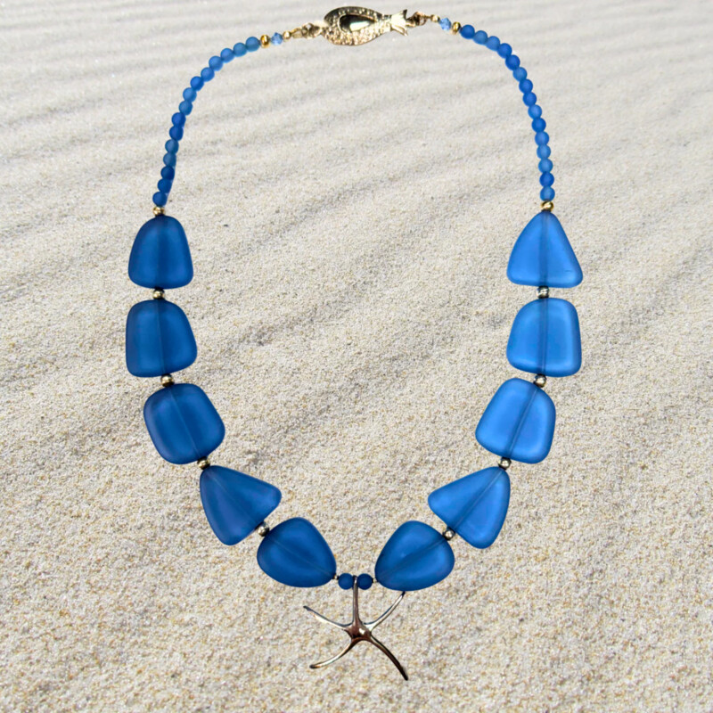 Red Sand Jewelry by Barbara Nymark<br />
Beautiful hand crafted in Victoria-By-The-Sea, PEI, Canada .925 Star Fish and Fishy<br />
Blue SeaGlass Necklace with Swarovski crystals and sterling silver.<br />
<br />
Size: 20 Inches