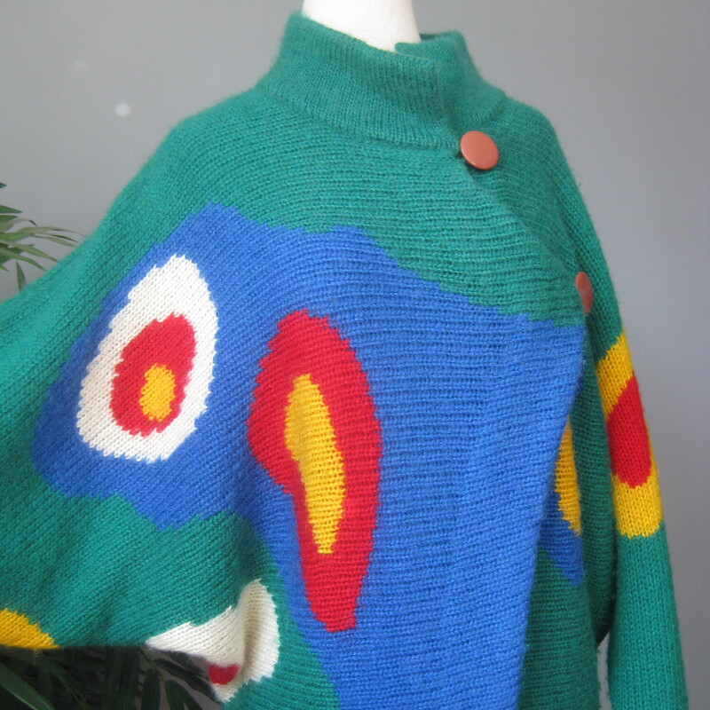 Dramatic and sophisticated colorblock cardigan sweater from Excel.<br />
Batwing sleeves, funnel neck<br />
Buttons somewhat asymmetrically at the top and bottom<br />
Surreal-esqe round shapes on the front sleeves and back in red, yellow, white and blue<br />
50% acrylic, 35% mohair, 15% nylon<br />
Excellent condition, no flaws<br />
Made in Hong Kong<br />
Marked Size 1, i don't know what that means but this sweater will fit a modern medium to large size person<br />
Here are the flat measurements, please double where appropriate:<br />
Armpit to armpit: 22 aprox.<br />
width at hem: 18 stretches comfortably to 21<br />
Length: 28.25, you can wear it bloused over at the waist if you button the bottom button.<br />
<br />
Thanks for looking!<br />
#76253