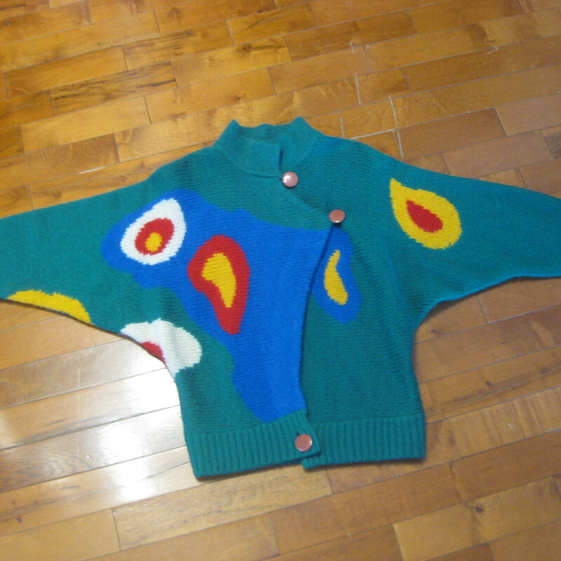 Dramatic and sophisticated colorblock cardigan sweater from Excel.<br />
Batwing sleeves, funnel neck<br />
Buttons somewhat asymmetrically at the top and bottom<br />
Surreal-esqe round shapes on the front sleeves and back in red, yellow, white and blue<br />
50% acrylic, 35% mohair, 15% nylon<br />
Excellent condition, no flaws<br />
Made in Hong Kong<br />
Marked Size 1, i don't know what that means but this sweater will fit a modern medium to large size person<br />
Here are the flat measurements, please double where appropriate:<br />
Armpit to armpit: 22 aprox.<br />
width at hem: 18 stretches comfortably to 21<br />
Length: 28.25, you can wear it bloused over at the waist if you button the bottom button.<br />
<br />
Thanks for looking!<br />
#76253