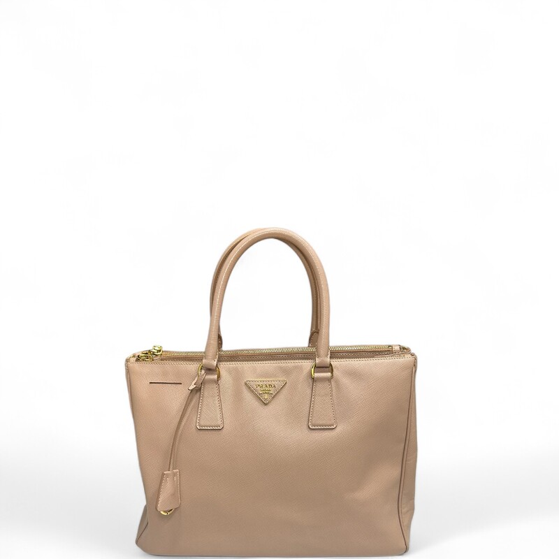 Prada Galleria Lux
 Nude
 Size: Medium

 This tote is crafted of saffiano lux cross-grain leather in pink beige. The bag features rolled leather top handles, an optional shoulder strap with polished gold plated links, and a hanging clochette. The top opens to two full-length top zippered compartments and a Prada monogram jacquard interior with zipper and patch pockets.

Dimensions:Base length: 13.5 in
Height: 9.75 in
Width: 5.5 in
Drop: 4.5 in
Drop: 16.5 in

Wear shown in photos