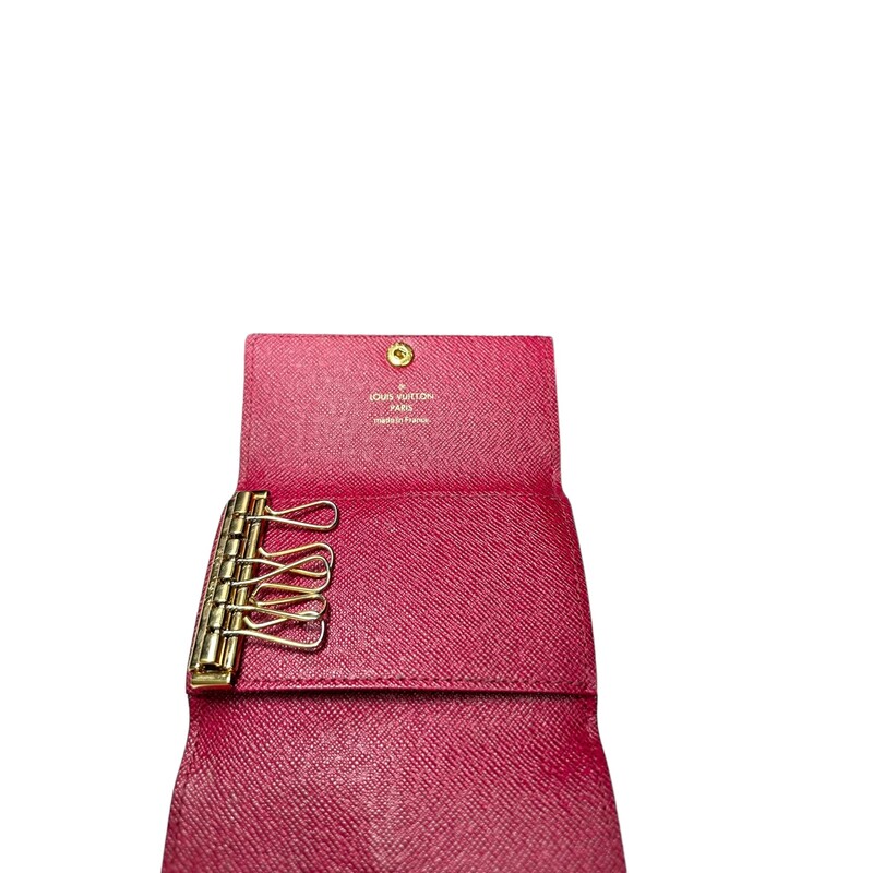 LOUIS VUITTON Monogram 6 Key Multicles Holder in Fuchsia. This stylish key holder is created of classic Louis Vuitton monogram on coated canvas and a gold snap button. It opens to a fuchsia cross grain leather interior with 6 brass key holders.
Dimensions:
Base length: 4.25 in
Height: 2.75 in
Width: 0.5 in
Code:
CT3290
Comes with dust bag and box