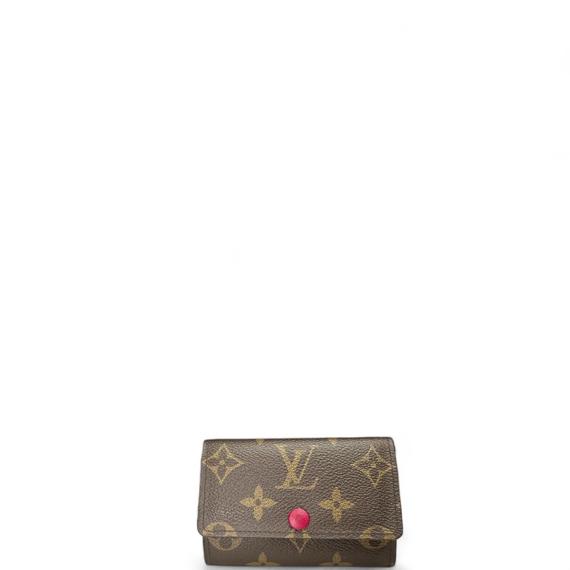 LOUIS VUITTON Monogram 6 Key Multicles Holder in Fuchsia. This stylish key holder is created of classic Louis Vuitton monogram on coated canvas and a gold snap button. It opens to a fuchsia cross grain leather interior with 6 brass key holders.
Dimensions:
Base length: 4.25 in
Height: 2.75 in
Width: 0.5 in
Code:
CT3290
Comes with dust bag and box