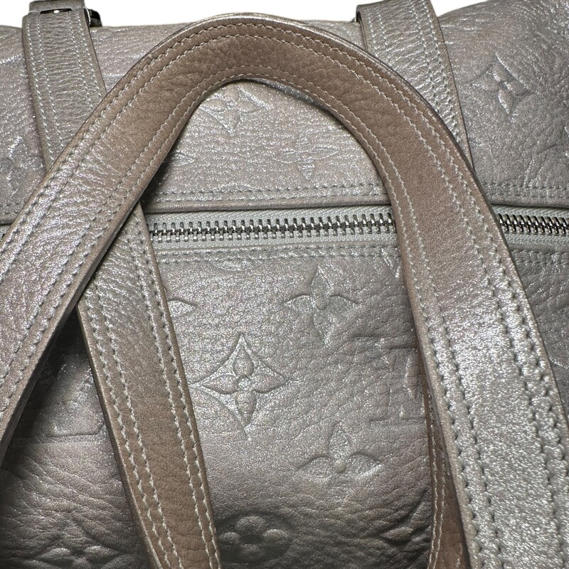 LOUIS VUITTON Monogram Shimmer Comete in Silver. This chic tote is crafted of Louis Vuitton metallic embossed light pink shimmery leather. The bag features leather straps with polished silver links and a decorative frontal silver plate from which is suspended a silver tipped leather tassel. The top zipper opens to a gray fabric interior with a patch pocket.

Dimensions:
Base length: 12 in
Height: 6.5 in
Width: 8 in
Drop: 9 in

Exterior: Some Discoloration/ fading,  and edge wear

Date Code: AR3068