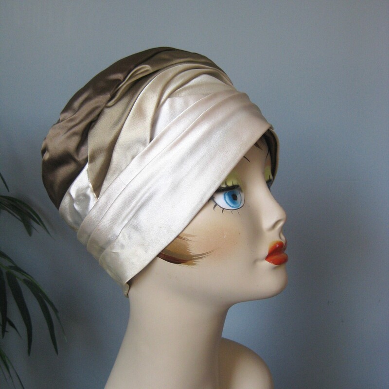 This dressy turban style hat is made of folded satin in shades of cream and taupe.
By Mr John
I found it at an estate sale in Norway Maine.
Excellent vintage condition.
Probably from the 1960s
Inner hat band measures: 21.5
Excellent condition, one faint stain as shown.

Thank you for looking.
#78414