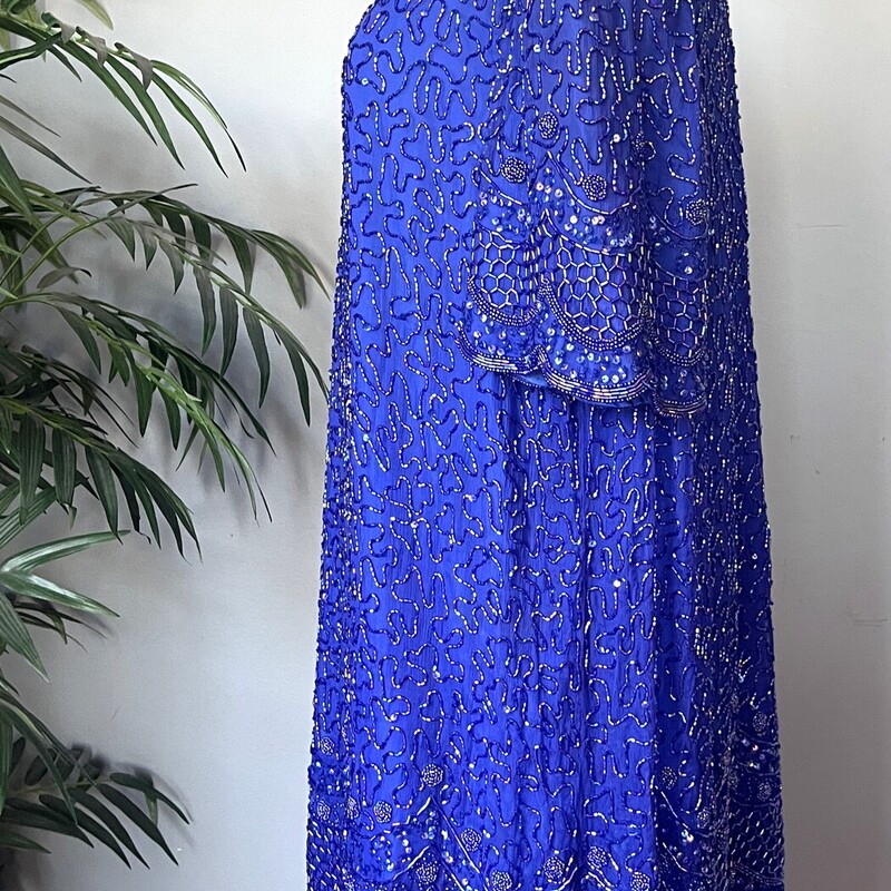 Floor length Silk Beaded Gown in royal blue. The dress was made in India. The base is silk.<br />
It has a two piece look - both 'pieces' are fully beaded.<br />
The tunic look top layer has a pretty scalloped hem.<br />
Short Sleeves and moderate shoulders to support the substantial weight of the dress.<br />
Kick vent in the back measures 18<br />
Center back zipper<br />
Brand: Brilliante<br />
<br />
marked size 1X<br />
Flat measurements:<br />
shoulder to shoulder: 18<br />
armpit to armpit: 23.5<br />
waist: 23.5<br />
hip: 24'<br />
length: 54<br />
Excellent vintage condition!<br />
Thanks for looking<br />
#76107