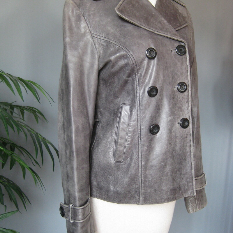 Guess Leather Moto, Gray, Size: Medium<br />
This simple hip length double breasted gray leather jacket has a bit of an edge but wearable to work and any other occasion.  Trench details, peacoat adjacet it's fully line with side pockets and straps at the end of the cuffs.<br />
Button closures<br />
It has pockets and a high and wide notched lapel<br />
<br />
Excellent pre-owned condition!<br />
It's marked size M, but I am calling it a small.  The measurements, as you will see are too small for a modern size M, I am a size medium and I tried it on and it was too snug for me all over.<br />
<br />
Here are the flat measurements:<br />
Shoulder to shoulder: 15.75<br />
Armpit to armpit: 19.5<br />
Width at hem: 18<br />
Length: 25<br />
underarm sleeve seam: 17<br />
<br />
Thanks for looking!<br />
#80698