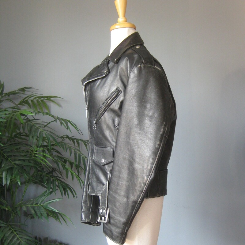 Vtg Dur O Jac Leather Mot, Black, Size: Medium<br />
Here's a classic black leather motorcycle jacket from Dur O Jac with silver hardware.  It has a buckling belt and silver zippers on the front, sleeves and pockets.<br />
I believe it dates from the 1980s<br />
This jacket is in perfect wearable condition, has been worn - a lot - well broken in.<br />
It has edgewear and scuffs in quite a few places but no deep scratches or missing or broken hardware.<br />
The jacket has quilted lining 3 zippered pockets on the front.<br />
Also 'ticket' pocket with a snap closure, this pocket is deeper than you might expect.  I don't think a modern phone will fit though.<br />
Shoulder epaullettes.<br />
Marked size M<br />
I am a medium, about size 10 this jacket is too tight on me.  So if you are a modern size 6 or 8 it should work for you.<br />
Flat measurements, please double where appopriate:<br />
Shoulder to shoulder : 18<br />
Armpit to armpit: 21<br />
Width at hem: 18<br />
Underarm sleeve seam: 18<br />
Length: 25<br />
<br />
Thank you for looking<br />
#80783