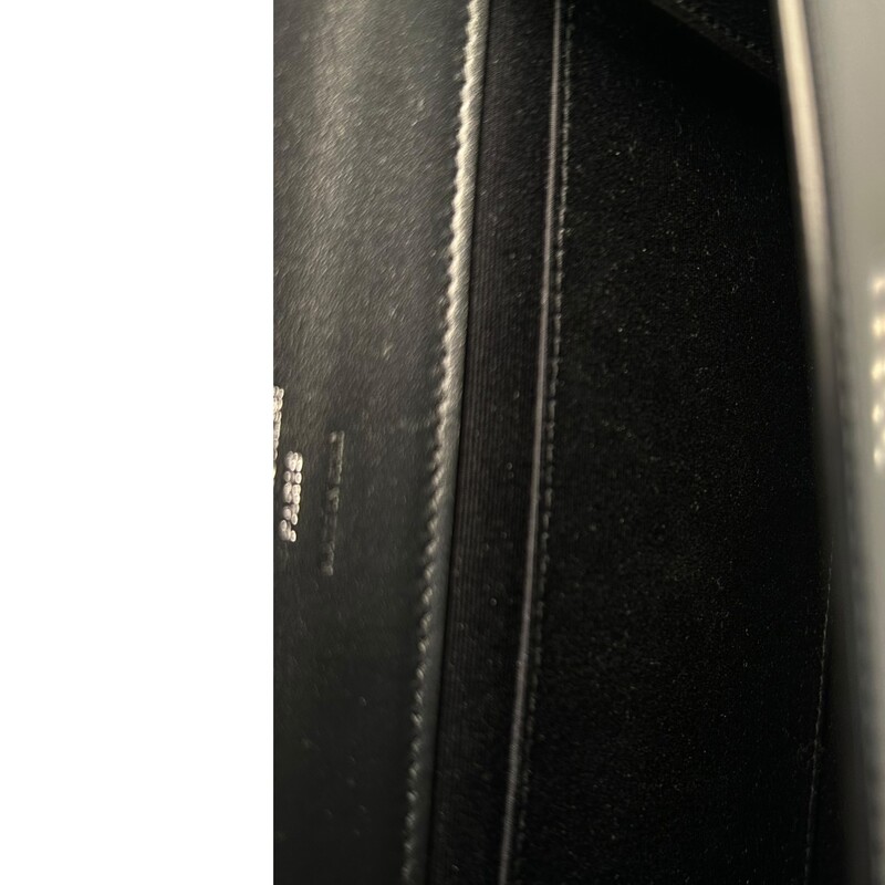 Saint Laurent Cassandre<br />
Shiny Black Leather<br />
Snap-button closure<br />
One main interior compartment, one flat pocket<br />
Grosgrain lining<br />
Silver hardwear<br />
Dimensions: 8.2W x 1.1D x 6.3H<br />
Code: GNC 760097.0923<br />
<br />
Comes with original dust bag and box.