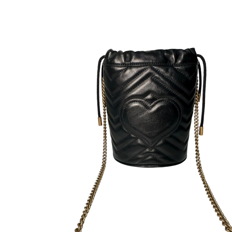 GUCCI Calfskin Matelasse Mini GG Marmont 2.0 Bucket Bag in Black. This soft-structured bucket bag is crafted of soft calfskin leather in black with a beautifully stitched chevron pattern. It features an aged gold chain shoulder strap, a top cinch cord and an aged gold interlocking GG logo. On the back of this beautifully crafted bag, there is a heart stitched design. This bag opens to a beige microfiber interior with card slots and a removable key ring.<br />
Dimensions:<br />
Base length: 5 in<br />
Height: 7 in<br />
Width: 4.25 in<br />
Drop: 22.5 in<br />
Condition: Some minor marks on the inside  otherwise in great shape