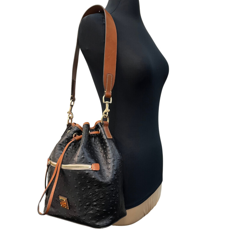 Dooney&Bourke  Ostrich Drawstring Handbag<br />
Embossed calfskin leather<br />
Drawstring closure.<br />
Detachable Shoulder strap. Strap drop length: 13.<br />
H 10.5 x W 5.25 x L 8.75<br />
1 lb 9 oz<br />
Designed in Norwalk, CT by Peter Dooney.<br />
One outside zip pocket. One inside zip pocket. Two inside pockets.<br />
Cell phone pocket.<br />
Inside key hook.<br />
Lined.<br />
Feet.<br />
Color: Black, and Tan