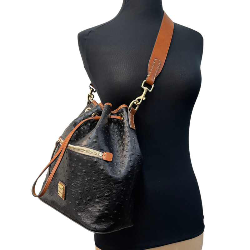 Dooney&Bourke  Ostrich Drawstring Handbag<br />
Embossed calfskin leather<br />
Drawstring closure.<br />
Detachable Shoulder strap. Strap drop length: 13.<br />
H 10.5 x W 5.25 x L 8.75<br />
1 lb 9 oz<br />
Designed in Norwalk, CT by Peter Dooney.<br />
One outside zip pocket. One inside zip pocket. Two inside pockets.<br />
Cell phone pocket.<br />
Inside key hook.<br />
Lined.<br />
Feet.<br />
Color: Black, and Tan