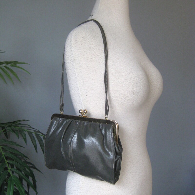 Chic gray leather bag by Shirl Miller a thin leather strap that you can wear on the shoulder, cross body or tucked to carry the bag like a clutch<br />
Sturdy shiny gold tone kiss lock frame<br />
Faille fabric lining with one zippered pocket<br />
Excellent condition, with some minor scratches on the gold frame<br />
Phone fits!<br />
W: 9<br />
H: 7<br />
Depth: aprox 1.5 the soft pouchy leather construction allows it toexpand when filled<br />
<br />
Thank you for looking!<br />
#80287