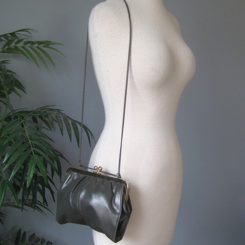 Chic gray leather bag by Shirl Miller a thin leather strap that you can wear on the shoulder, cross body or tucked to carry the bag like a clutch<br />
Sturdy shiny gold tone kiss lock frame<br />
Faille fabric lining with one zippered pocket<br />
Excellent condition, with some minor scratches on the gold frame<br />
Phone fits!<br />
W: 9<br />
H: 7<br />
Depth: aprox 1.5 the soft pouchy leather construction allows it toexpand when filled<br />
<br />
Thank you for looking!<br />
#80287