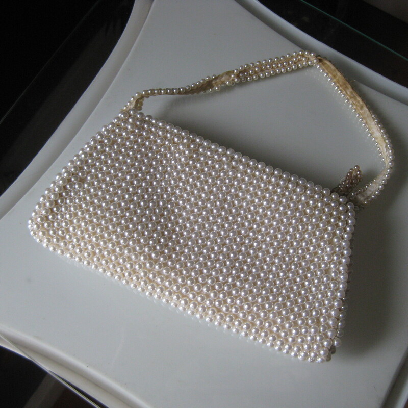 Teeny little vintage handbag, most likely made in Japan.  It's covered with white faux earls and it has an inset of smoky bugle beads in a curved design.<br />
The handle is also beaded and it has a top zipper.<br />
super narrow, it won't hold much.<br />
It came to me in a gift box, presumable from the store at which is was purchased way back when.  With age, (20's?) the matrix has darkened in the bottom right corner to a yellowy brown color.<br />
<br />
It's so small, you may be able to fit an old fashioned key and a lipstick in it, you can put some change in it for your bridge game, or use it as a keepsake bag or hide some money in as a pretty gift for a young lady.  Or maybe let the flower girl use it at the wedding.  She'll love it!<br />
<br />
Width: 7.5 at the bottom, 6 at the top<br />
Height: 4<br />
handle drop: 4<br />
<br />
thanks for looking!<br />
#81441