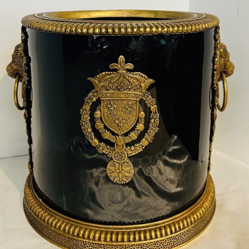 Bronze Mounted Champagne Bucket<br />
Black Gold<br />
Size: 10x10H<br />
Twentieth Century, Empire Style Ormolu mounted<br />
black porcelain champagne bucket having lion heads opposing sides with ring handles and coat of arms in-between with United Wilson 1897 market to underside.<br />
Heavy