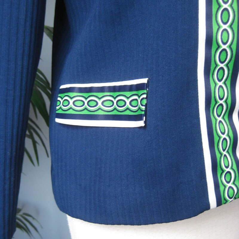 Here's a topper for someone who loves retro style. This big shirt or open cardigan is made of poly double knit, sturdy and pretty warm, washer and dryer safe. It's blue with green and white geometric contrast trim.<br />
It has decorative pocket flaps on the front (no working pockets) and a single hook and eye closure at the neck.<br />
Unlined<br />
No tags<br />
A little bit of stretch<br />
<br />
Here are the flat measurements, please double where appropriate:<br />
<br />
Shoulder to shoulder: 16<br />
armpit to armpit: 20<br />
Length: 24.75<br />
<br />
Thanks for looking!<br />
#73285