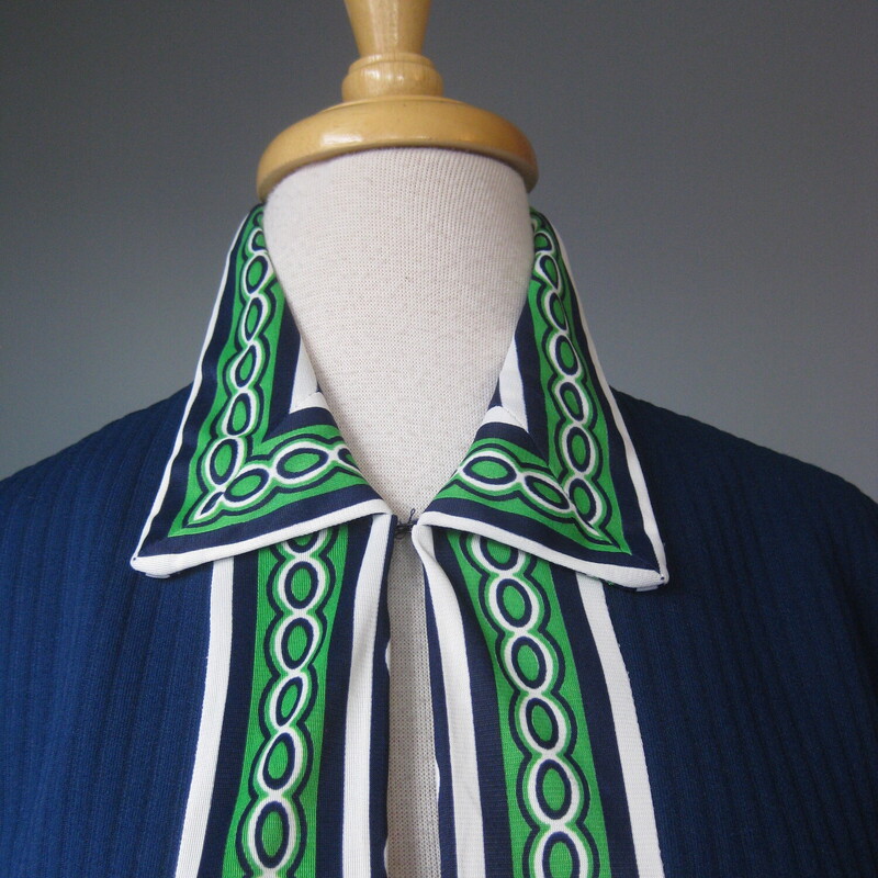 Here's a topper for someone who loves retro style. This big shirt or open cardigan is made of poly double knit, sturdy and pretty warm, washer and dryer safe. It's blue with green and white geometric contrast trim.<br />
It has decorative pocket flaps on the front (no working pockets) and a single hook and eye closure at the neck.<br />
Unlined<br />
No tags<br />
A little bit of stretch<br />
<br />
Here are the flat measurements, please double where appropriate:<br />
<br />
Shoulder to shoulder: 16<br />
armpit to armpit: 20<br />
Length: 24.75<br />
<br />
Thanks for looking!<br />
#73285