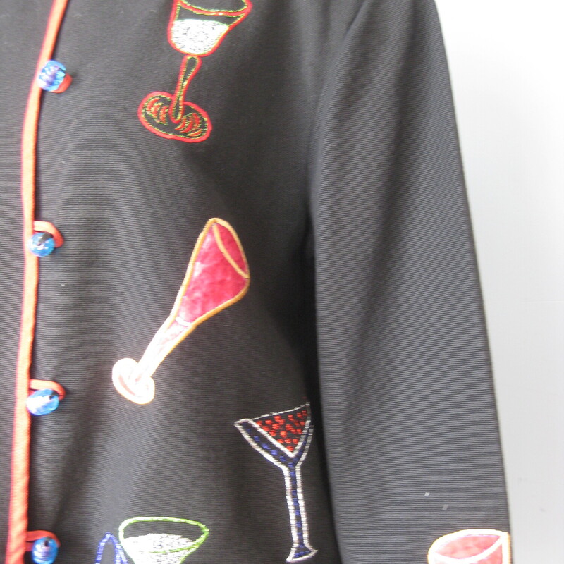 Nice jacket to wear on New Years Eve !<br />
High quality medium weight cotton with colorful barware and drinks embroidered all over it.<br />
Trimmed in red edging<br />
The embellishements continue on the back of the jacket and the sleeves<br />
Pretty blue plastic beads and loops down the front.<br />
Fully lined in polyester<br />
by Daniel K , Made in India<br />
Marked size LK<br />
<br />
Flat measurements:<br />
shoulder to shoulder: 17.5<br />
armpit to armpit: 22.75<br />
width at hem while buttoned: 23<br />
length: 25.75<br />
underarm sleeve seam: 17.25<br />
<br />
thanks for looking!<br />
#41870