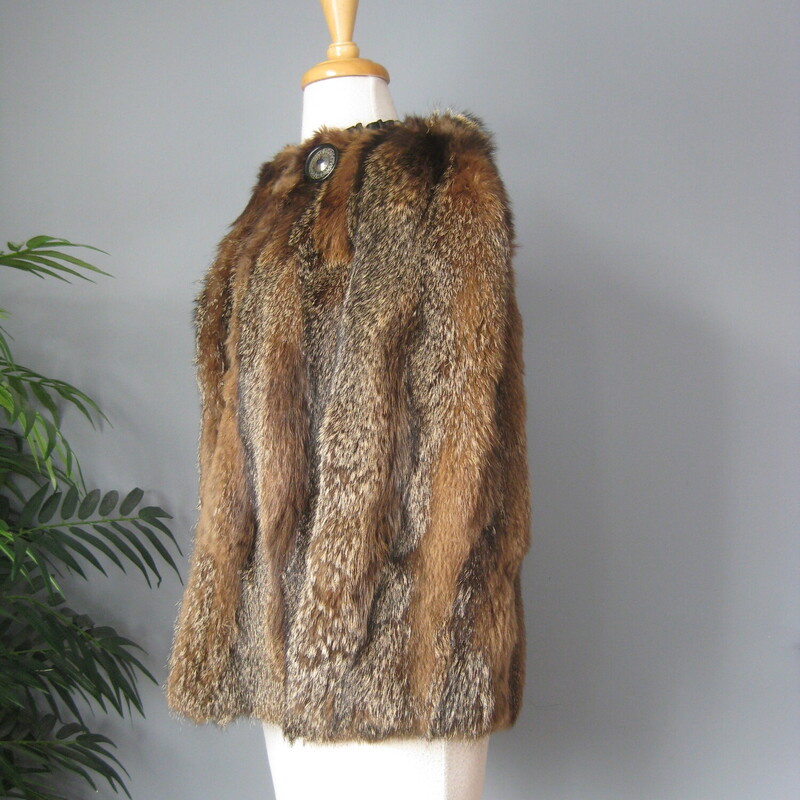 Make a statement in this striking vintage fur jacket.<br />
The fur which I think is mainly raccoon is beautifully matched and composed with vertical strips of a the stiffer variegated fur alternating with strips of a super soft and less structured fur.<br />
<br />
Fully lined<br />
Wide 3/4 sleeves<br />
It has one hook and eye at about the center of the front and fancy button at the neck, unfortunately the loop for that button is broken. But other the jacket is in excellent condition!<br />
Flat measurements, taken on the inside of the jacket.<br />
Armpit to armpit : 20<br />
Length: 24.5<br />
Thanks for looking.<br />
#82680