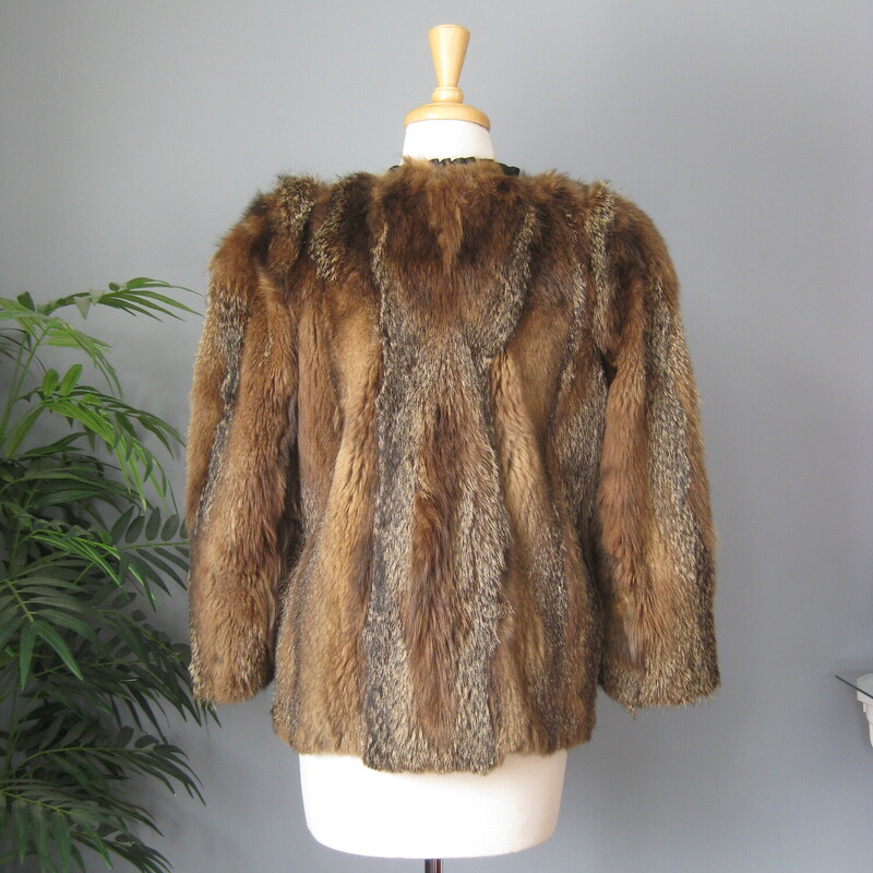 Make a statement in this striking vintage fur jacket.<br />
The fur which I think is mainly raccoon is beautifully matched and composed with vertical strips of a the stiffer variegated fur alternating with strips of a super soft and less structured fur.<br />
<br />
Fully lined<br />
Wide 3/4 sleeves<br />
It has one hook and eye at about the center of the front and fancy button at the neck, unfortunately the loop for that button is broken. But other the jacket is in excellent condition!<br />
Flat measurements, taken on the inside of the jacket.<br />
Armpit to armpit : 20<br />
Length: 24.5<br />
Thanks for looking.<br />
#82680