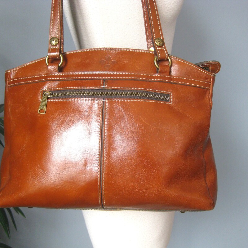 Understated Patricia Nash brown leather bag<br />
Great for work and travel.<br />
lots of pockets, secure top zipper<br />
double handles<br />
outside it has one zippered pockets and 2 big slip pockets<br />
inside it has two elasticized slip pockets and one zippereped pocket<br />
Her classic microfiber, suede like lining.<br />
bottom studs.<br />
<br />
13.5 x 11.5 x 3.25<br />
handle drop: 11<br />
<br />
Good used condition. there's a curved marke on the one side and a shallow scratch (or leather imperfection?) on the other.<br />
also some corner wear<br />
Please view all of the photos.<br />
thanks for looking!<br />
#83445