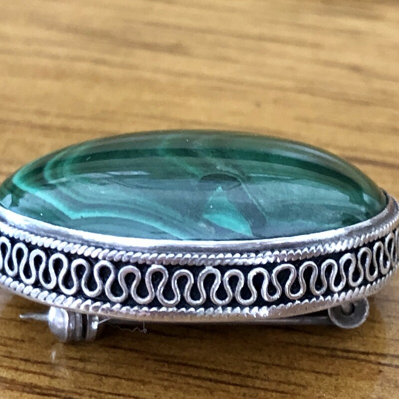 The malachite in this vintage brooch is a rich green confection of waving lines, a beautiful oval of hunter and kelly hued stripes. The ribbon of silver encircling the stone completes this wonderful Mid-Century era  brooch.<br />
Size: 1.25in X 1in