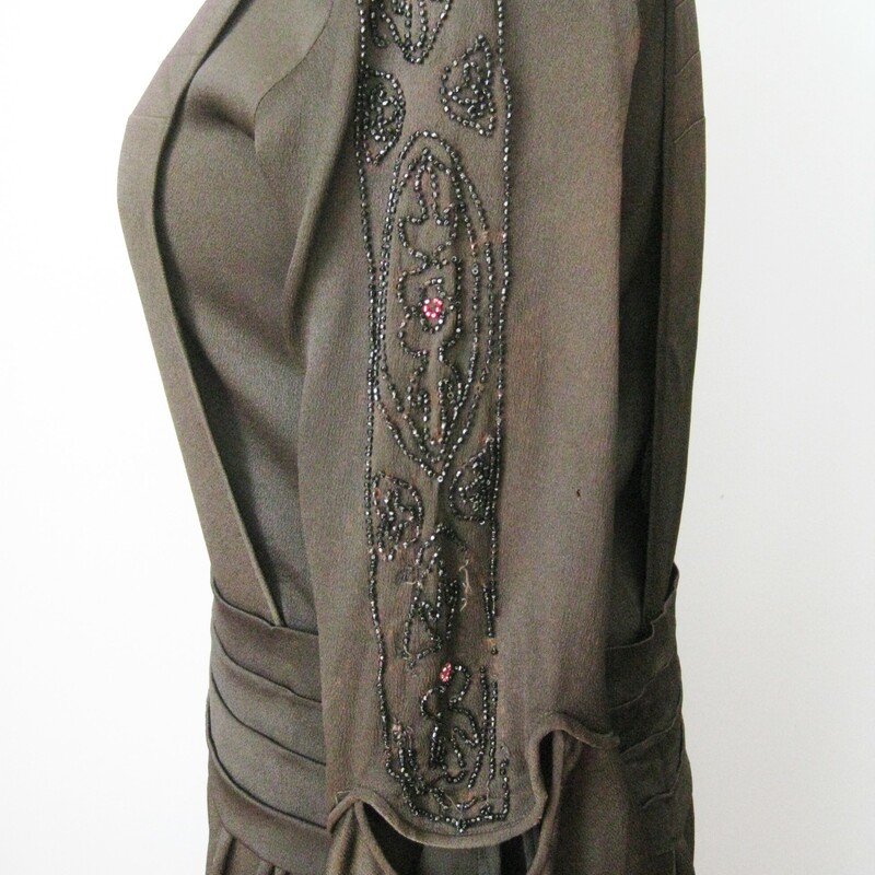 This is an antique dress from the 1920s, possibly earlier.
This dress has a straight dropped waist silhouette and super interesting construction
Two part sleeves, the upper part is beautiufully beaded in small jet beads and some pink rocaille beads.
There is a panel of the same beading hanging from each side of the hip area, these are attached at the hips and free to swing as you move.
The front panel snaps just over the left shoulder and at the cummerbund.
Underneath the front panel is an under shirt that fastens with hooks and eyes.
Unlined

CONDITION: please read.
Fabric deterioration - especially under the beading on one of the hip panels.  I think this could be stablized with some black lightweight interfacing applied very carefully to the back.  I did not dare to attempt.
Piping on one sleeve has some minor damage
The black has faded on the front panel so it looks a little red
Perspiration stains visible
Pinholes through out the skirt, easily camoflaged with a black slip.

This delicate dress is for someone who knows what they're doing and can restore it. Or you can buy it to display.  You could wear it as well.  It looks perfectly lovely until you start inspecting carefully.  PLease don't hesitate to contact me with any questions you might have.

Here are the flat measurements, please double where appropriate:

Shoulder to shoulder: 15 1/2in
Armpit to armpit: 17in
Waist: 16in
Hip: 22in
Length: 42in

Thank you for looking.
#10961