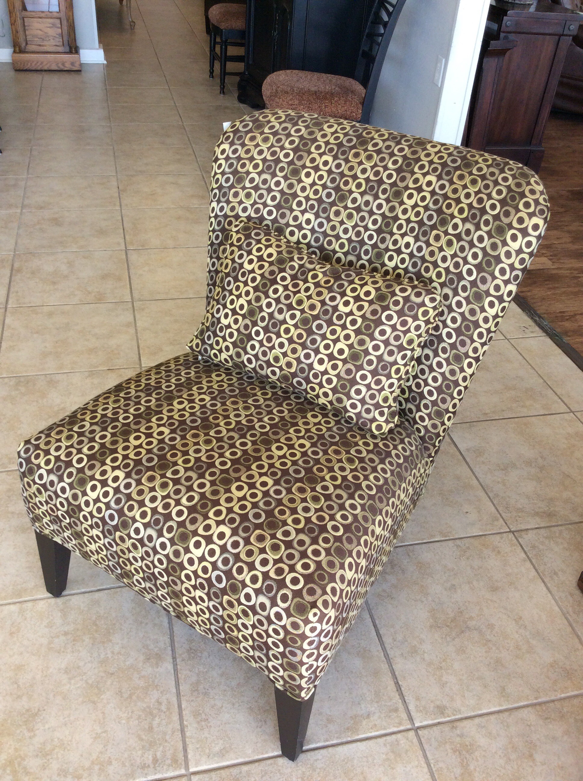 This pretty slipper chair has been upholstered in a modern geometric pattern of brown, gold and green. It comes with an accessory pillow.