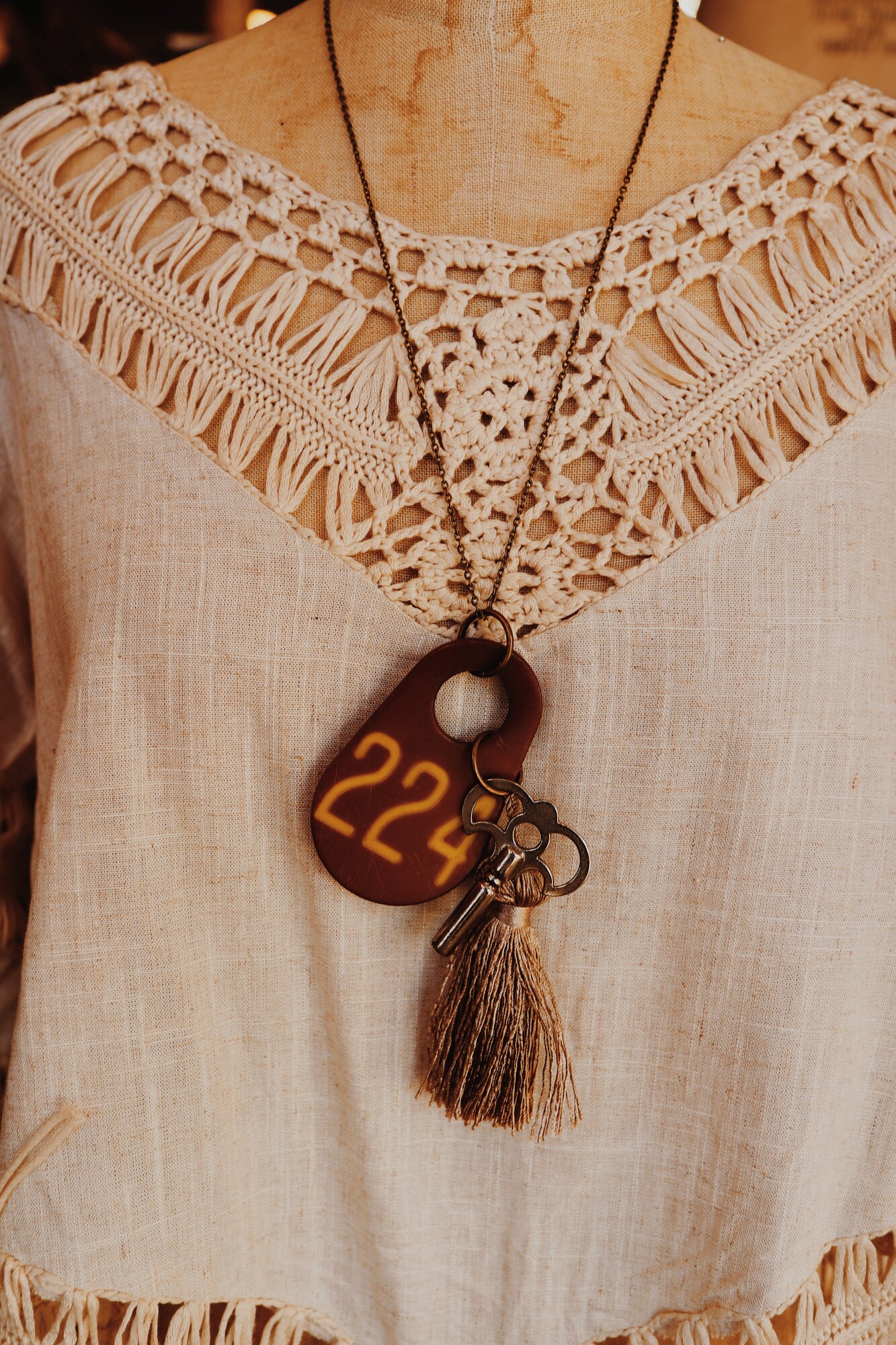 This one of a kind, handmade necklace has a cowtag with 224 on it, as well as a silver key and tassle. It hangs from a 26 inch chain.