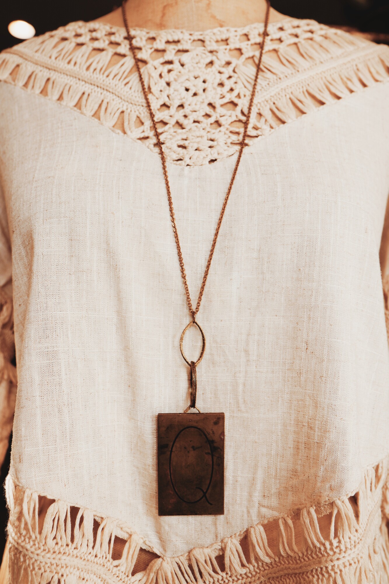 This unique necklace has a Q engraved brass plate. It hangs on a 32 inch chain.