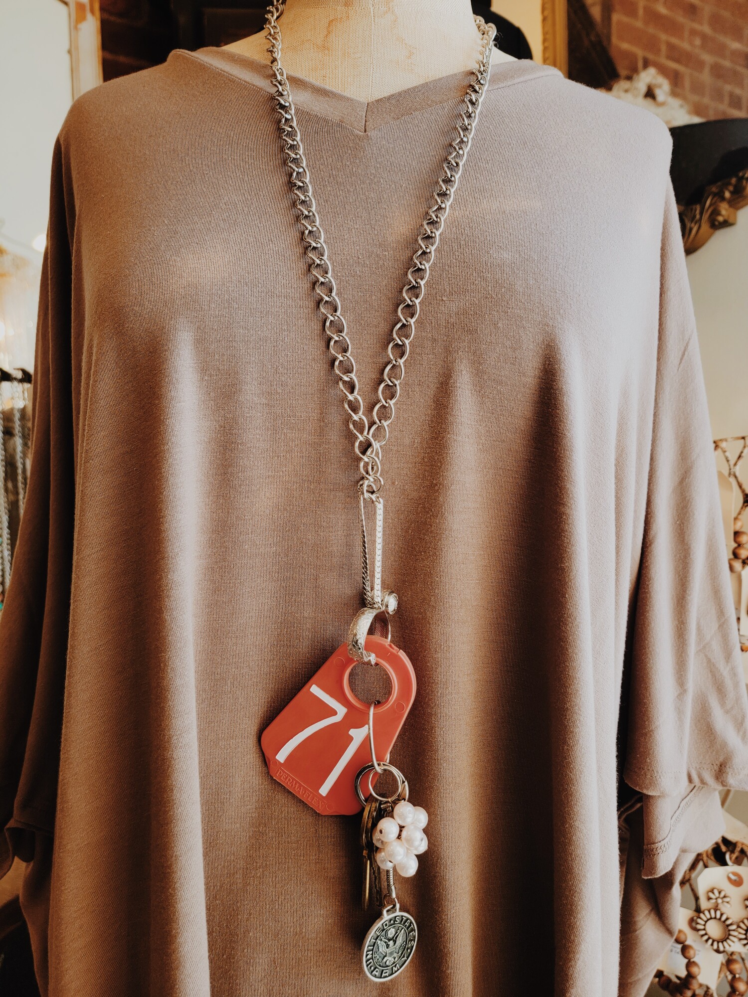This one of a kind neccklace has a red cow tag with a 71 on it, three brass keys, a United States Army coin, and a chain of pearls. This all hangs on a 33 inch chain.