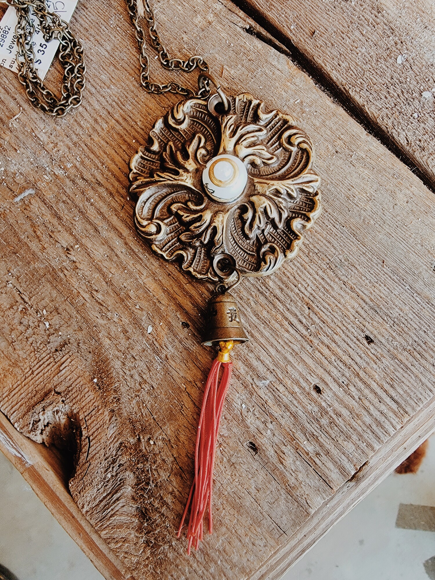- Hand crafted necklace
- 32 Inch chain
- Red 2 inch tassel
- Brass flower pendant with pearl center